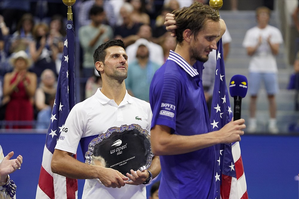 Novak Djokovic, of Serbia, holds the runner-up trophy as Daniil Medvedev, of Russia, prepares to receive the championship trophy after Medvedev defeated Djokovic in the men's singles final of the US Open tennis championships, Sunday, Sept. 12, 2021, in New York. (AP Photo/John Minchillo)