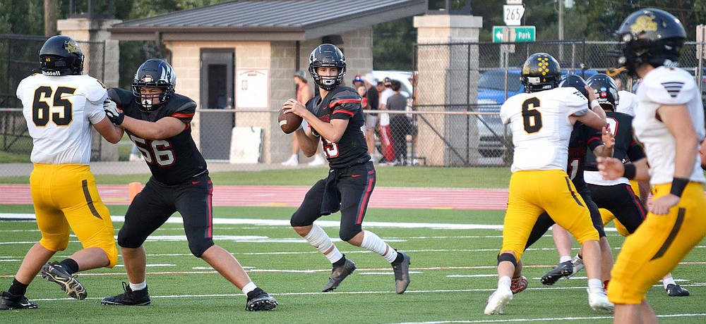 Sophomore quarterback Gavin Dixon, No. 15, prepares to pass as he is guarded by Blackhawks Braidon McCarley, No. 56, left, and Joe Adams, No. 2, right, Friday, Sept. 10, 2021.