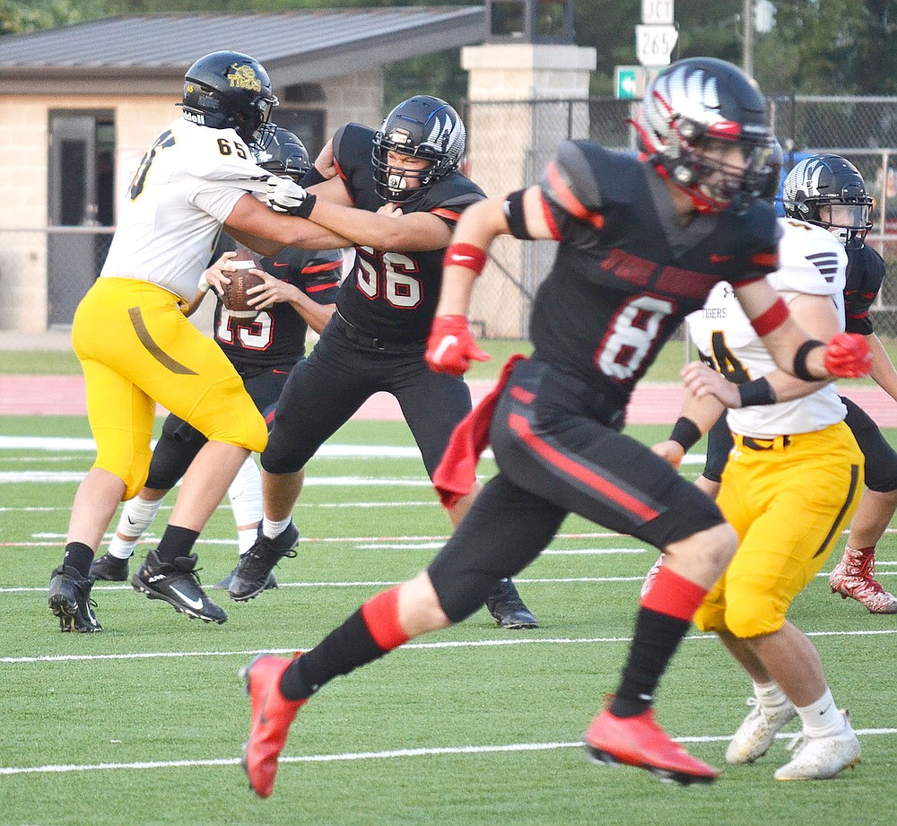 Senior Blackhawk Braidon McCarley, No. 56, holds back a Tiger defender as quarterback Gavin Dixon, No. 15, prepares to pass and wide receiver Trevor Blair, No 8, heads downfield to receive.