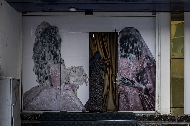 An Afghan woman enters a beauty salon in Kabul, Afghanistan, Saturday, Sept. 11, 2021. Since the Taliban gained control of Kabul, several images depicting women outside beauty salons have been removed or covered up. (AP Photo/Bernat Armangue)