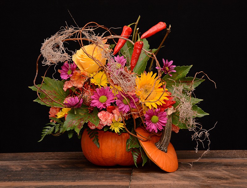 For a festive fall centerpiece, try hollowing out a pumpkin. Drop in a plastic liner or a glass vase filled with floral foam. Fill the foam with seasonal flowers, branch material, Spanish moss and dried peppers or pepper berries. Prop the pumpkin top against the arrangement as a finishing touch. (Courtesy of Rittners Floral School)