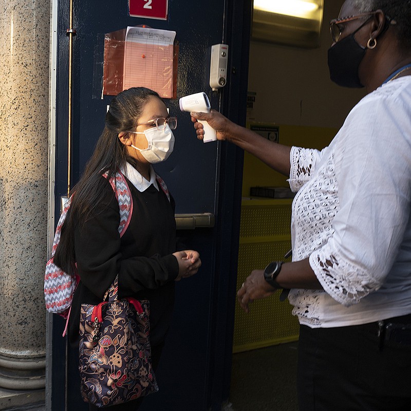 A girl has her temperature checked as she arrives for the first day of school at Brooklyn's PS 245 elementary school, Monday, Sept. 13, 2021, in New York. Classroom doors are swinging open for about a million New York City public school students in the nation's largest experiment of in-person learning during the coronavirus pandemic. (AP Photo/Mark Lennihan)