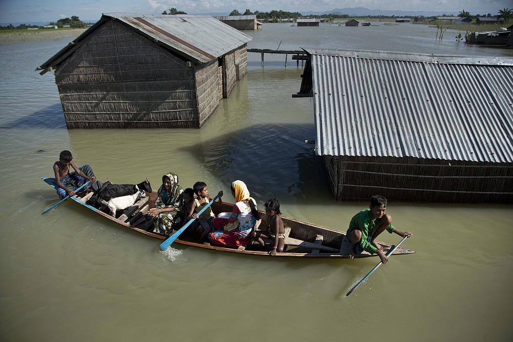 FILE - In this July 31, 2016, file photo, a flood-affected family with their goats travel on a boat in the Morigaon district, east of Gauhati, northeastern Assam state, India. Climate change could push more than 200 million people to move within their own countries in the next three decades and create migration hotspots unless urgent action is taken in the coming years to reduce global emissions and bridge the development gap, a World Bank report has found. The report published on Monday, Sept. 13, 2021 examines how long-term impacts of climate change such as water scarcity, decreasing crop productivity and rising sea levels could lead to millions of what the report describes as “climate migrants” by 2050. (AP Photo/Anupam Nath, File)