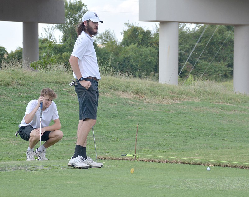 Graham Thomas/Herald-Leader
Siloam Springs seniors Miles Perkins (left) and Brayden Fain line up putts during Monday's match at The Course at Sager's Crossing.