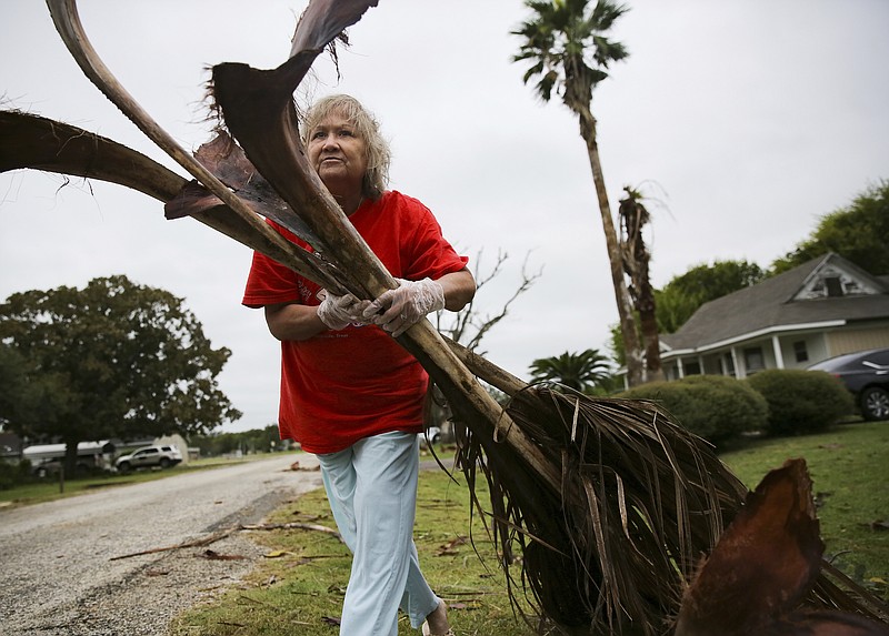 Alfa Alamia cleans up her brother's yard in Palacios, Texas following Hurricane Nicholas on Tuesday, Sept. 14, 2021. Alamia has lived in Palacios since she was 12. (Elizabeth Conley/Houston Chronicle via AP)