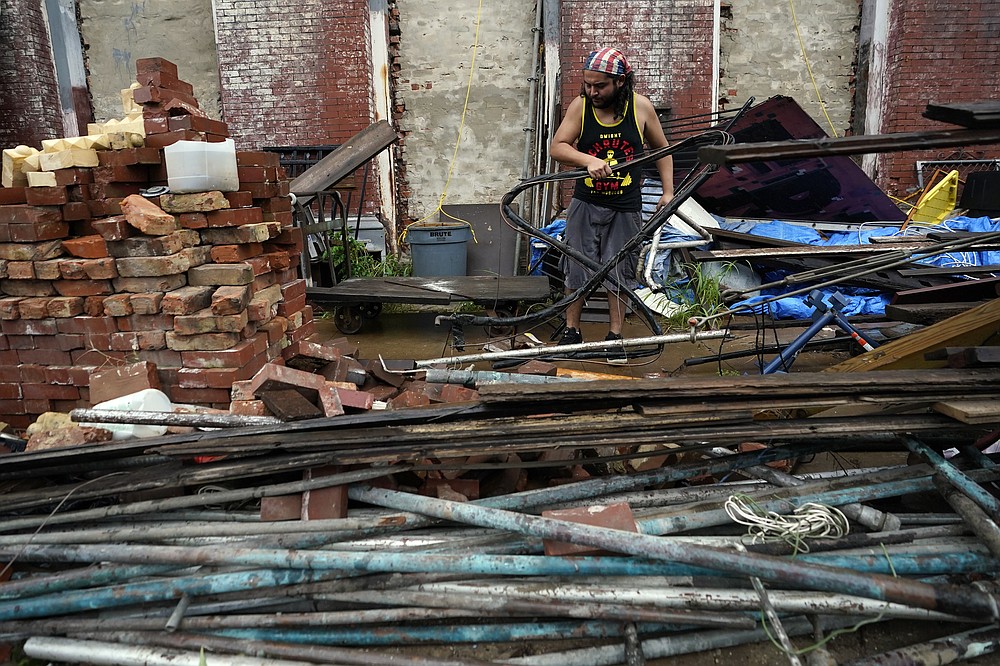 Adrian Bentancourt cleans up debris from a fence that was blow down by Hurricane Nicholas Tuesday, Sept. 14, 2021, in Galveston, Texas. (AP Photo/David J. Phillip)