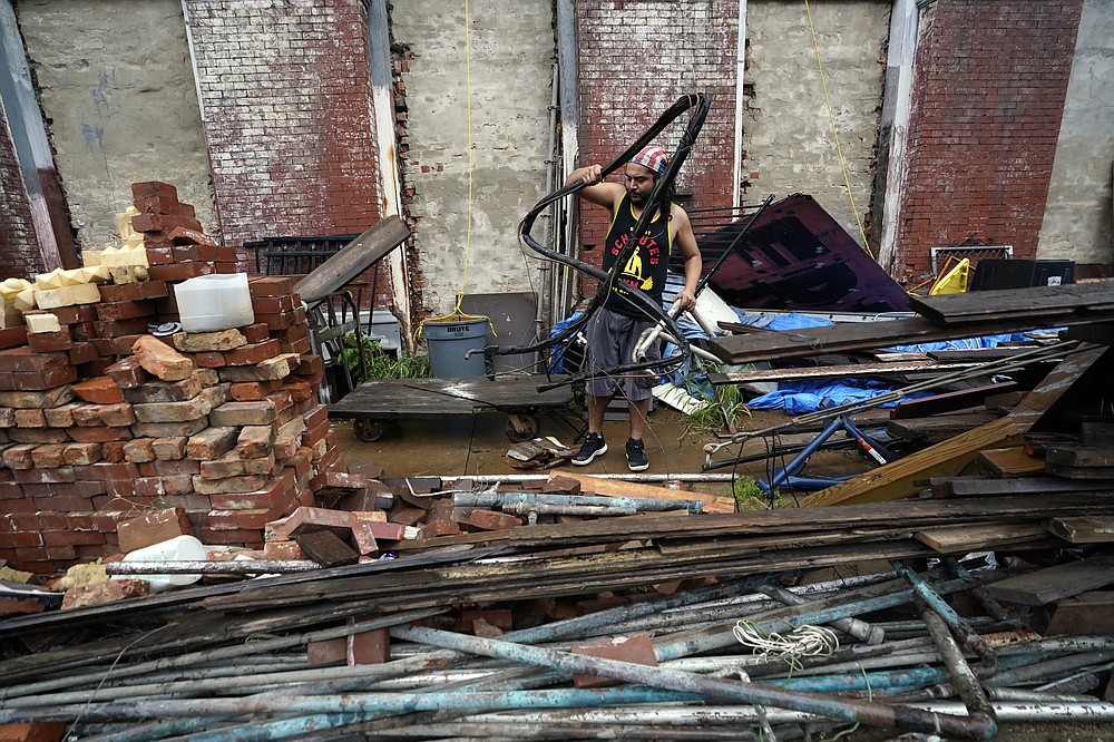 Adrian Bentancourt cleans up debris from a fence that was blown down by Hurricane Nicholas Tuesday, Sept. 14, 2021, in Galveston, Texas. (AP Photo/David J. Phillip)