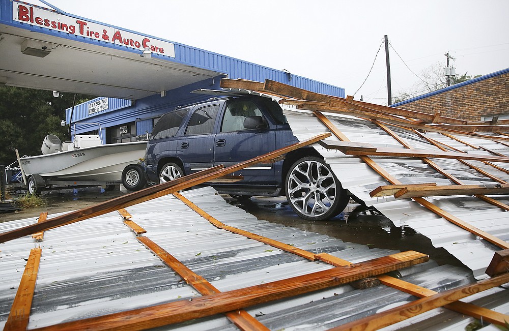 Parts of a roof sit on top of a car parked at Blessings Tire and Auto Care following Hurricane Nicholas in Bay City, Texas on Tuesday, Sept. 14, 2021. According to the owner of the business, he wasn't sure where the roof came from. (Elizabeth Conley/Houston Chronicle via AP)