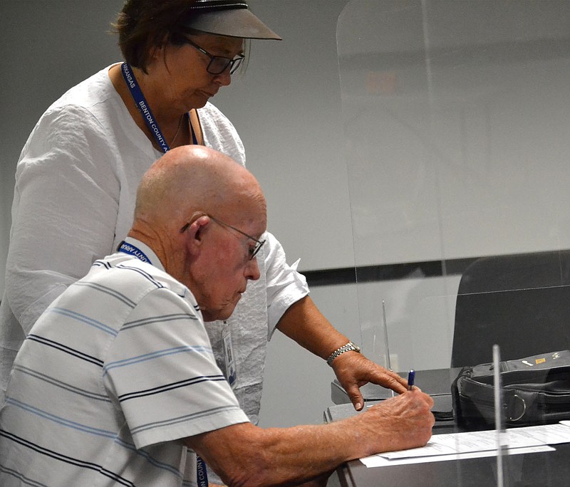 Robbyn Tumey, election commissioner, hands election forms to Harlan Stee, commissioner, to sign Tuesday night in the Benton County Election Commission office.