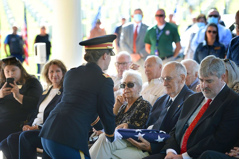 Robert Mitchell, 90, of Fort Smith presentes a flag Tuesday during a military burial ceremony for his brother, 2nd Lt. Henry Donald Mitchell of Harmon, at the Fayetteville National Cemetery. Robert Mitchell led a decades-long effort to find the remains of his brother, whose Lockheed P-38 Lightning went down July 8, 1944 while serving with the 48th Fighter Squadron over Austria during World War II, and have to them returned to Arkansas for burial. 
(NWA Democrat-Gazette/Andy Shupe)