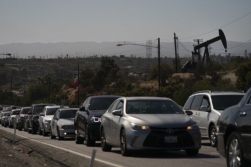 Motorists wait for a signal to change as pump jacks extract oil at the Inglewood Oil Field, Thursday, June 10, 2021, in Los Angeles. (AP Photo/Jae C. Hong)