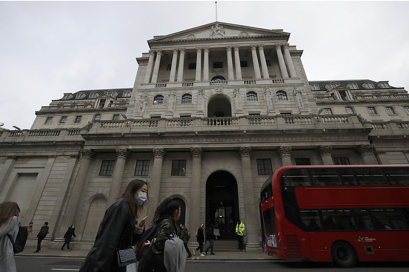 FILE - In this Wednesday, March 11, 2020 file photo, pedestrians wearing face masks walk past the Bank of England in London. The U.K. posted the biggest jump in annual inflation on record last month as global supply shortages and rising wages magnified the scale of price increases after pandemic-related discounts a year ago. (AP Photo/Matt Dunham, File)