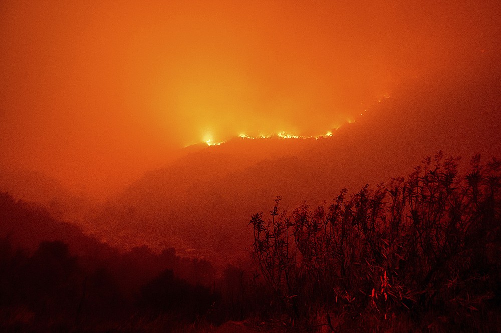 Flames from the KNP Complex Fire burn along a hillside above the Kaweah River in Sequoia National Park, Calif., on Tuesday, Sept. 14, 2021. The blaze is burning near the Giant Forest, home to more than 2,000 giant sequoias. (AP Photo/Noah Berger)
