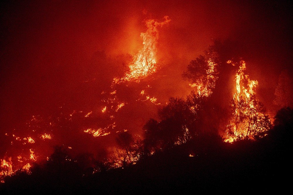 Flames from the KNP Complex Fire burn a hillside above the Kaweah River in Sequoia National Park, Calif., on Tuesday, Sept. 14, 2021. The blaze is burning near the Giant Forest, home to more than 2,000 giant sequoias. (AP Photo/Noah Berger)