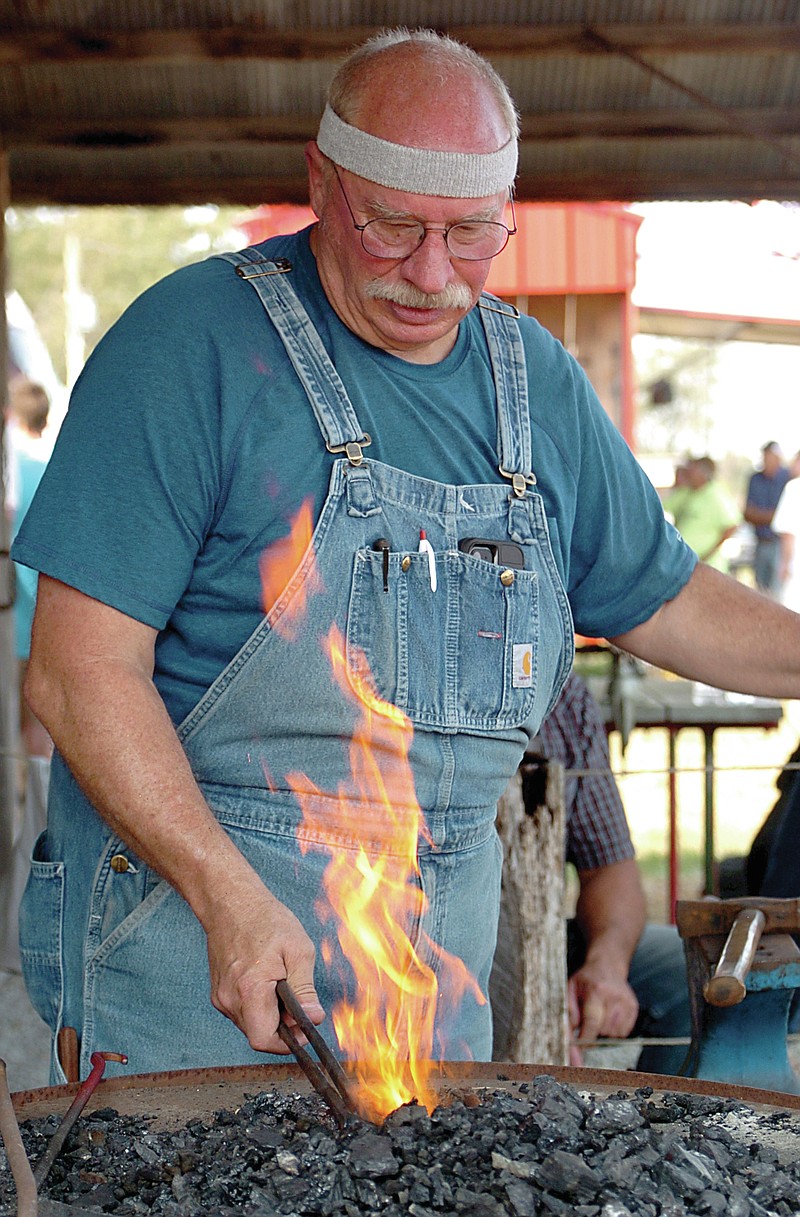 3e5e3wqWestside Eagle Observer/RANDY MOLL
Lin Rhea, of Prattsville, a member of the American Bladesmith Association, heats up a piece of iron as he demonstrates the art to a crowd of visitors Saturday at the Tired Iron of the Ozarks fall show in Gentry. Members of the American Bladesmith Association and the Blacksmith Organization of Arkansas were at the annual show and talking with spectators on Saturday.