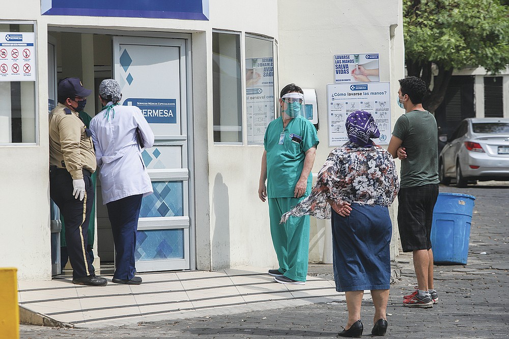 FILE - In this May 11, 2020 file photo, a medical worker wears a mask and face shield at the entrance of the SERMESA hospital in Managua, Nicaragua. While the Pan-American Health Organization urges Nicaragua to take more aggressive measures against the coronavirus pandemic and neighboring countries warily eye its outbreak, President Daniel Ortega’s increasingly authoritarian government seems more focused on hiding the virus than treating it. (AP Photo/Alfredo Zuniga, File)