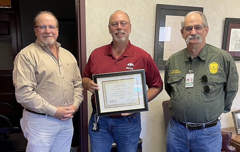 Garland County 911 Communications Center Director Corky Martin, center, displays his honorable mention citation for the Glenn “Sonny” Cox Award for Excellence in Public Safety Communications. He’s pictured with County Judge Darryl Mahoney, left, and Office of Emergency Management Deputy Director Bobby King. - Submitted photo