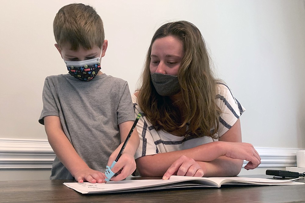 Emily Goss reviews schoolwork at the kitchen table with her five-year-old son inside their home in Monroe, NC on Monday, September 13, 2021. The Gosses have decided to go to school at home in Berkeley after the Union County School District chose not to implement a mask warrant for the children.  (AP Photo / Sarah Blake Morgan)