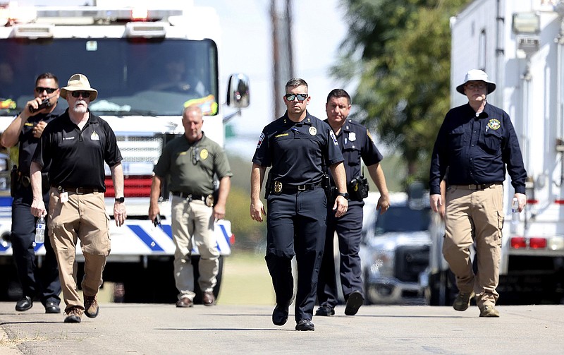 Lake Worth Police Chief J.T. Manoushagian, center, walks down Foster Drive near the location where a military training jet crashed on Sunday, Sept. 19, 2021, in Lake Worth, Texas. The jet crashed Sunday in a neighborhood near Fort Worth, Texas, injuring the two pilots and damaging three homes but not seriously hurting anyone on the ground, authorities said. (Amanda McCoy/Star-Telegram via AP)