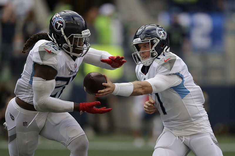 Tennessee Titans quarterback Ryan Tannehill, right, hands off to running back Derrick Henry during the second half of an NFL football game against the Seattle Seahawks, Sunday, Sept. 19, 2021, in Seattle. The Titans won 33-30 in overtime. (AP Photo/John Froschauer)