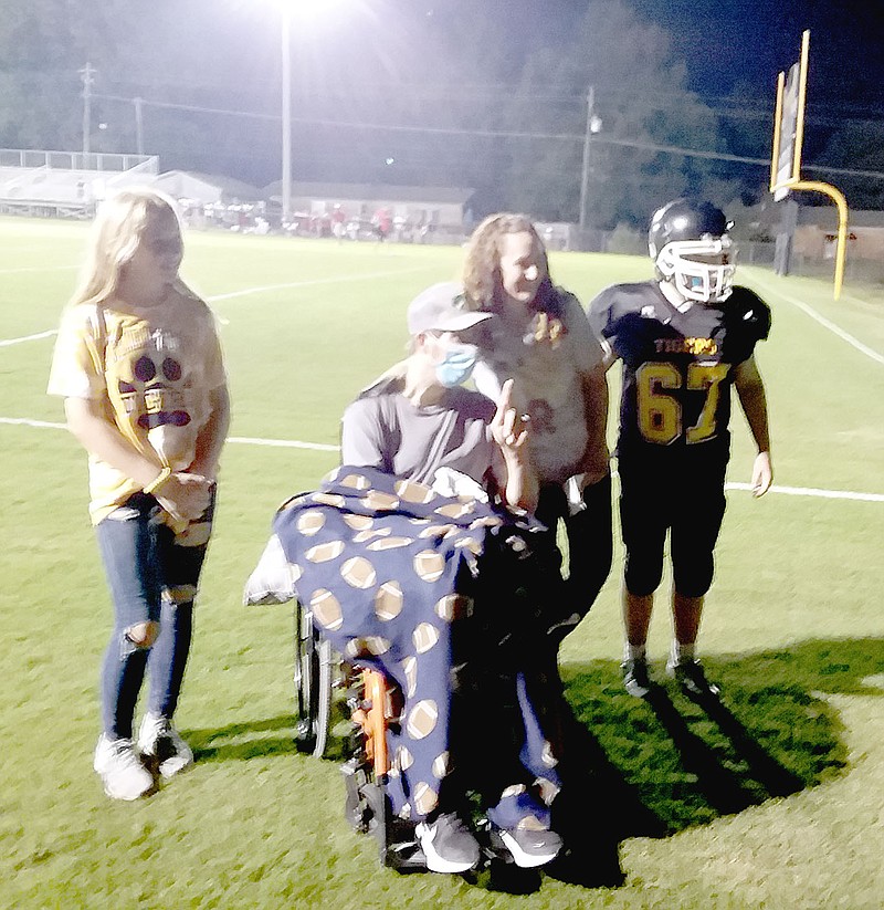 MARK HUMPHREY ENTERPRISE-LEADER/Dustin Dougan came out in a wheelchair to cheer on his son, Parker Dougan, a ninth grader (right), and the Prairie Grove junior Tigers in the &#x201c;Battle of 62&#x201d; rivalry game against Farmington on Thursday, Sept. 2. The game went down to the wire with Farmington winning 24-22, but Dustin Dougan&#x2019;s presence represented a miracle as he battles through health challenges that affected his physical capabilities and the removal of his left eye. Dustin was accompanied by his wife, Shelley, and daughter, Payton Dougan, a sixth grader.