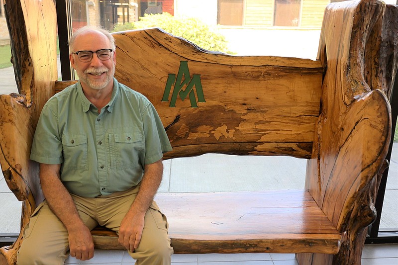 Phillip Tappe, retired UAM College of Forestry, Agriculture and Natural Resources dean, sits on the newly donated champion persimmon tree bench crafted as a promise by George Rheinhardt. (Special to The Commercial/University of Arkansas at Monticello)