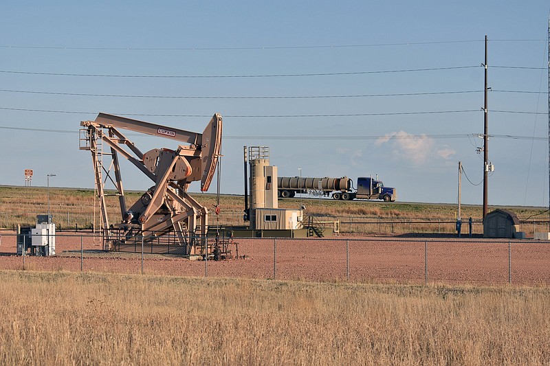 A pumpjack is seen extracting crude oil from a well while a tanker truck passes on by on a highway near New Town, N.D. on the Fort Berthold Indian Reservation on Tuesday May 18, 2021. A federal judge ruled Friday, May 21, 2021 that the Dakota Access oil pipeline may continue operating while the U.S. Army Corps of Engineers conducts an extensive environmental review.