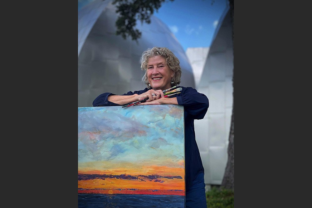 Landscape artist Mary Louise Porter poses with her painting “December Sunset.” (Special to the Democrat-Gazette)