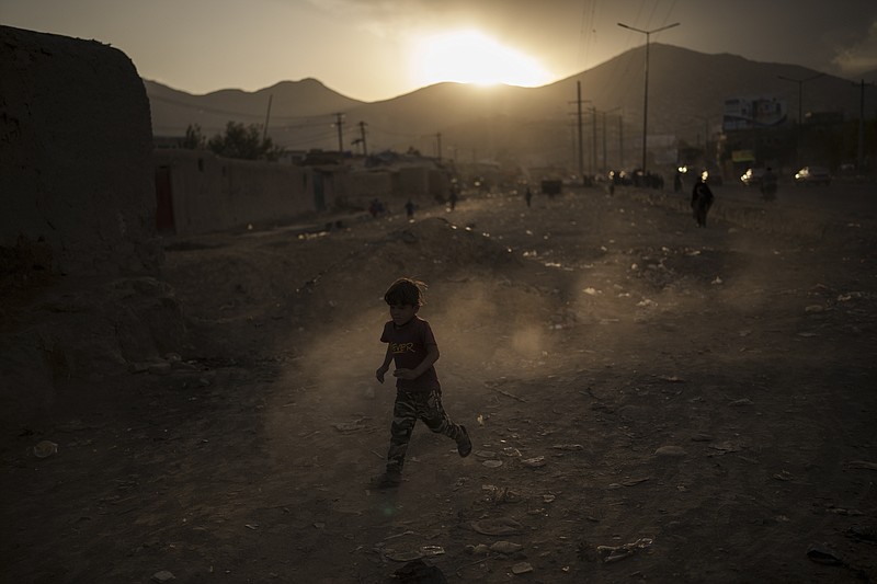 An Afghan boy plays on the side of a road as the sun sets in Kabul, Afghanistan, Wednesday, Sept. 22, 2021. (AP Photo/Felipe Dana)