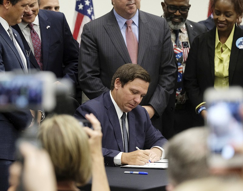 FILE - In this Friday, June 14, 2019, file photo, Florida Gov. Ron DeSantis signs the Sanctuary City bill at the Okaloosa County, Fla., commission chambers in Shalimar Fla. The bill requires all law enforcement agencies in Florida to cooperate with federal immigration authorities. U.S. District Judge Beth Bloom on Tuesday, Sept. 21, 2021, rejected parts of the 2019 law banning local government sanctuary policies and requiring local law enforcement to make their best efforts to work with federal immigration authorities. (Michael Snyder/Northwest Florida Daily News via AP, File)
