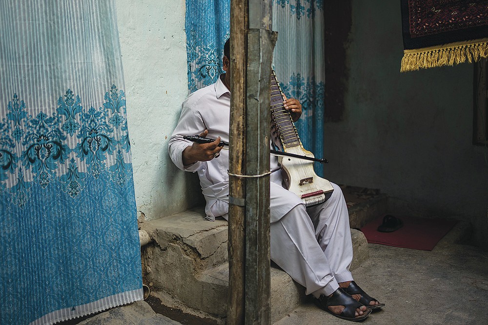 An Afghan musician poses for a portrait with his dilruba in Kabul, Afghanistan, Saturday, Sept. 18, 2021. About a month after the Taliban seized power in Afghanistan, the music is starting to go quiet. The last time that the militant group ruled the country, in the late 1990s, it outright banned music. (AP Photo/Bernat Armangue)