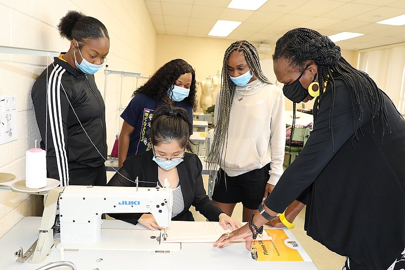 Students from the University of Arkansas at Pine Bluff?s Principles of Apparel Design class learn sewing machine techniques. Instructor Yunru Shen, at the sewing machine, works with students, from left, Jaia James, Dajah Williams and Brittney Eskridge and Professor Doze Y. Butler. (Special to The Commercial/University of Arkansas at Pine Bluff)