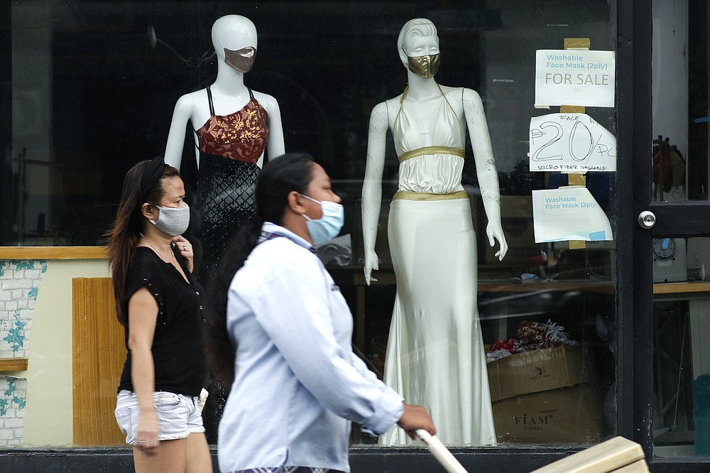 FILE - In this Sept. 29, 2020, file photo, women walk past mannequins wearing face masks advertised for sale, at a shop in Makati city, Philippines. Developing economies in Asia will likely grow at a slower pace than earlier expected due to prolonged COVID-19 outbreaks and uneven progress in vaccinations, the Asian Development Bank said in a report Wednesday, Sept. 22, 2021.(AP Photo/Aaron Favila, File)
