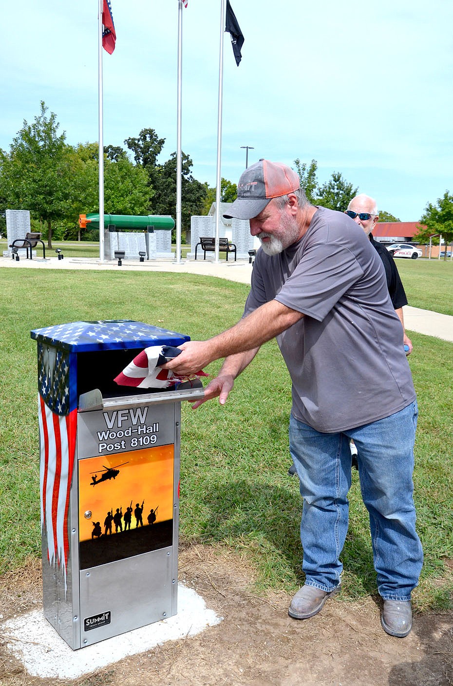Purvis Cope, who refurbished and painted the flag drop box for the Wood-Hall Veterans of Foreign Wars, placed a tattered flag in the box Friday, just after it was unveiled.