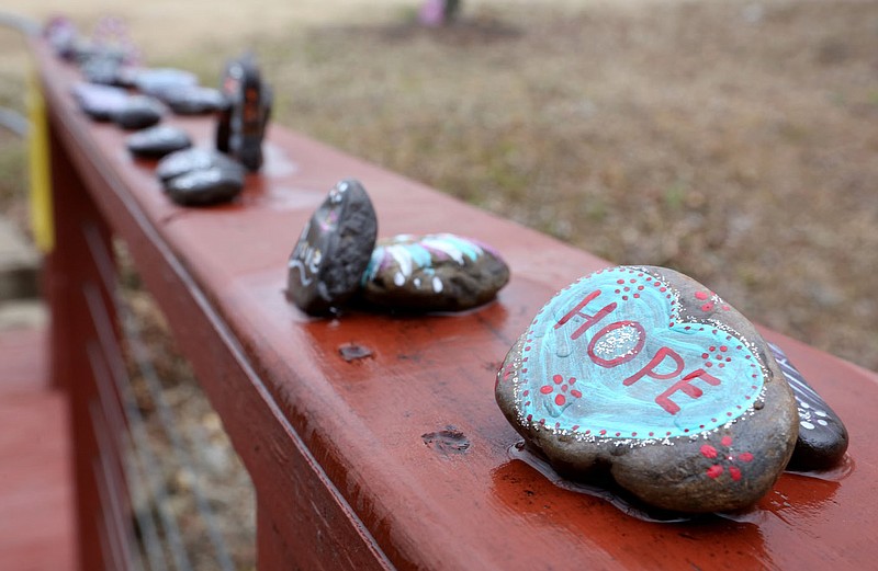 Decorated rocks are seen Jan. 27 on the hand rail of a foot bridge on the campus of Washington Regional Medical Center in Fayetteville. Health officials project new daily covid-19 cases will decline, although intensive care at area hospitals remains high.
(File photo/NWA Democrat-Gazette/David Gottschalk)