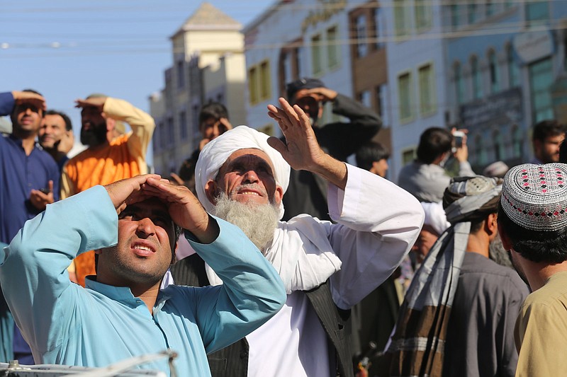 CORRECTS DAY TO SEPT 25 - People look up at a dead body hanged by the Taliban from a crane in the main square of Herat city in western Afghanistan, on Saturday Sept. 25, 2021. A witness told The Associated Press that the bodies of four men were brought to the main square and three of them were moved to other parts of the city for public display. The Taliban announced in the square that the four were caught taking part in a kidnapping and were killed by police.?(AP Photo)