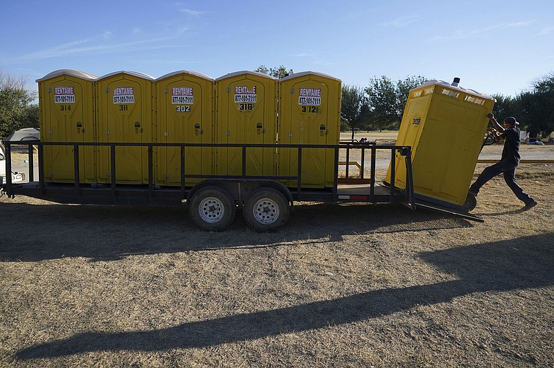 A worker loads portable toilets on a flat bed trailer Saturday for transport to a new rmigrant shelter in Ciudad Acuna, Mexico. 
(AP/Fernando Llano)