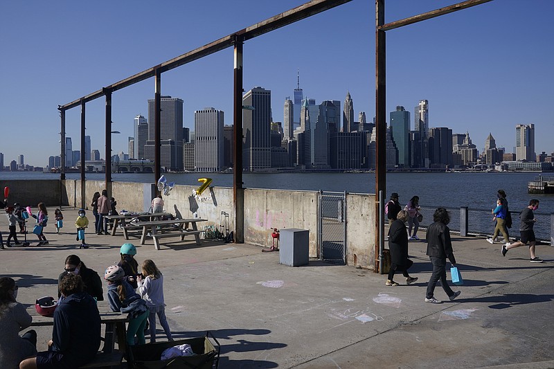 In this March 21 file photo, people enjoy the sunny weather and a view of the Manhattan skyline from the Brooklyn waterfront in New York. The surge in the nation’s urban population could give these urban centers greater influence in reshaping the balance of power in Washington as congressional redistricting gets under way. New York in particular is giving Democrats hope. The most populous city in the United States added some 629,000 new residents. - AP Photo/Seth Wenig