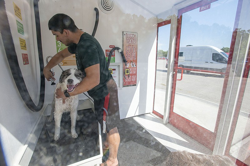 Phillip Alderete washes his dog Daisy Monday at Hutchís Pet Wash on College Ave. in Fayetteville. The self-service pet washing booth is in the parking lot of Lokomotion Family Fun Park and is open 24 hours a day. (NWA Democrat-Gazette/J.T. Wampler)