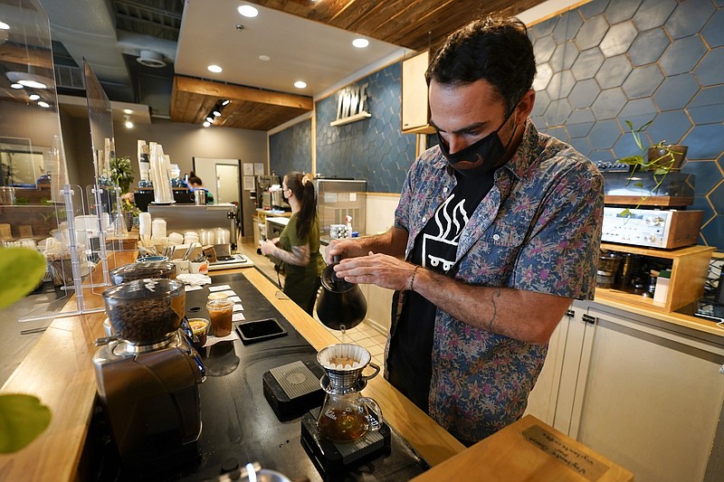 Chris Vigilante makes a dripped coffee for a customer at one of his coffee shops, Wednesday, Sept. 1, 2021, in College Park, Md. A confluence of supply chain problems, drought, frost and inflation all point to the price of your cup of morning coffee going up.