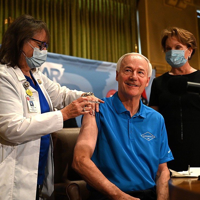 Neldia Dycus, regional director at the state Health Department, gives Gov. Asa Hutchinson his covid-19 booster shot Tuesday as first lady Susan Hutchinson waits to get hers before the start of the governor’s weekly briefing. More photos at arkansasonline.com/929gov/.
(Arkansas Democrat-Gazette/Stephen Swofford)
