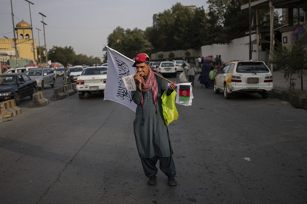 A street vendor sells Taliban and Afghan flags on a street in Kabul, Afghanistan, Thursday, Sept. 30, 2021. (AP Photo/Bernat Armangue)