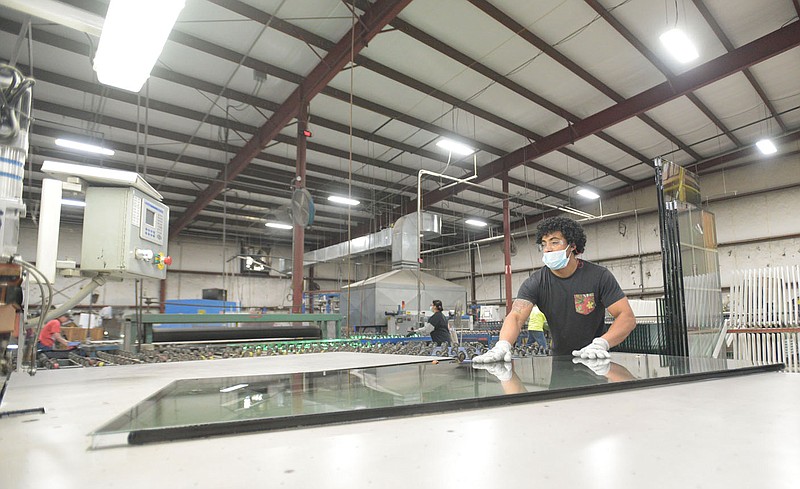 Erick Funes-Beltran, an employee at WeatherBarr Windows and Doors, works on a sheet of glass Friday morning in Fort Smith. WeatherBarr, which is undergoing a $10 million expansion of its facility, is one of several local manufacturers facing challenges related to worker retention and the supply chain amid the covid-19 pandemic.
(NWA Democrat-Gazette/Hank Layton)