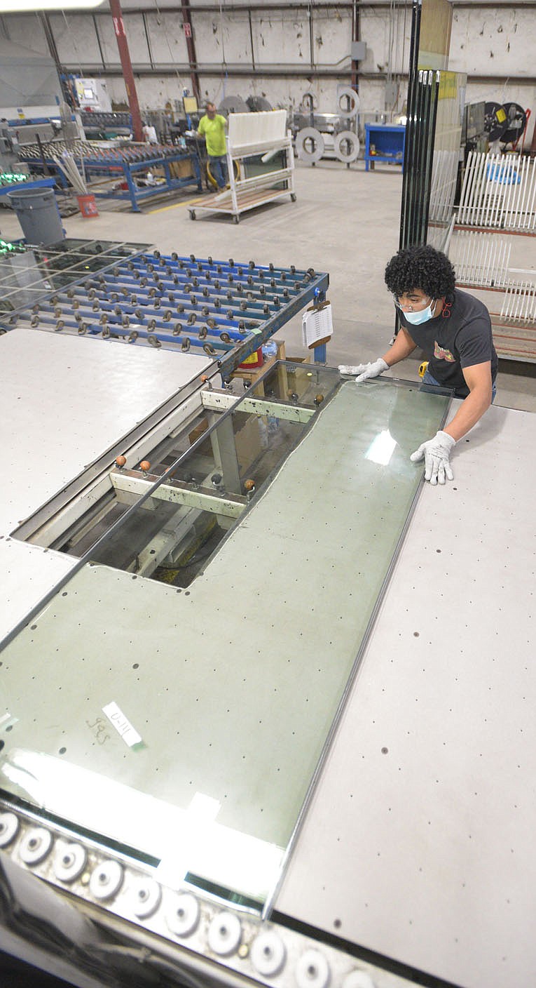 Erick Funes-Beltran, an employee at WeatherBarr Windows and Doors, works on a sheet of glass Friday morning in Fort Smith. WeatherBarr, which is undergoing a $10 million expansion of its facility, is one of several local manufacturers facing challenges related to worker retention and the supply chain amid the covid-19 pandemic.
(NWA Democrat-Gazette/Hank Layton)
