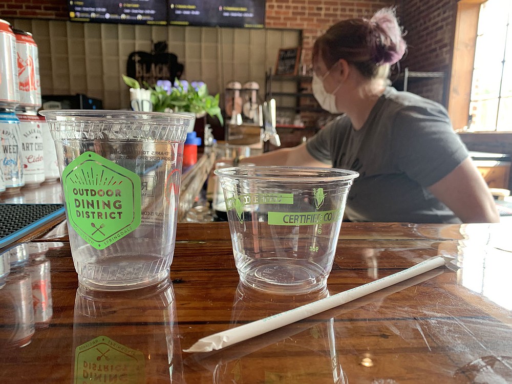 Alicia Beilby, tap room assistant at Black Apple, shows the compostable straws and drink containers Friday, Sept. 24, 2021, that are used by the business in Springdale. The Boston Mountain and Benton County solid waste districts are trying to gather more information from small businesses and offer them more ways to recycle. Go to nwaonline.com/211003Daily/ for today's photo gallery.
(NWA Democrat-Gazette/Andy Shupe)