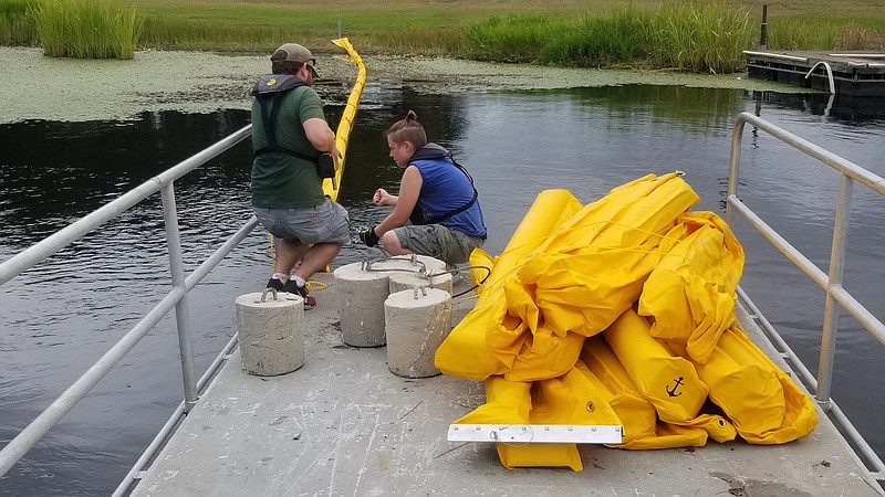 AGFC biologists out of its Camden office put out containment booms on Lake Columbia to help with giant salvinia. (Photo by AGFC)