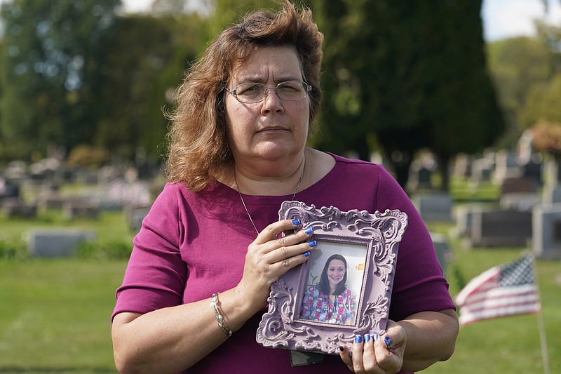 Sharon Grover holds a photograph of her daughter, Rachael, at Fairview Cemetery, Tuesday, Sept. 28, 2021, in Mesopotamia, Ohio. Grover believes her daughter started using prescription painkillers around 2013 but missed any signs of her addiction as her daughter, the oldest of five children, remained distanced.  (AP Photo/Tony Dejak)