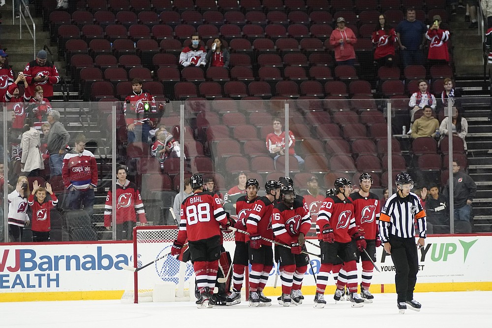 The Washington Capitals bench watches as New Jersey Devils' Jimmy Vesey  (16) scores an empty net goal during the third period of an NHL preseason  hockey game, Monday, Oct. 4, 2021, in