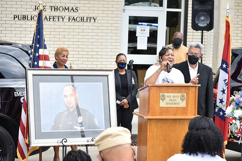 Dornetta "Donna" Hobbs speaks about her son, slain Pine Bluff Police Det. Kevin Collins (pictured in frame) as Mayor Shirley Washington (background, from left), Deputy Police Chief Denise Richardson and Interim Police Chief Lloyd Franklin Sr. listen outside police headquarters Tuesday, Oct. 5., 2021. (Pine Bluff Commercial/I.C. Murrell)