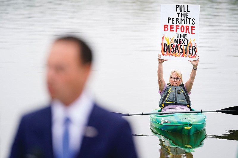 Libby Madarasz displays a placard as Pennsylvania Attorney General Josh Shapiro speaks during a news conference Tuesday at Marsh Creek State Park in Downingtown, Pa.. Shapiro filed criminal charges Tuesday against the developer of a problem-plagued pipeline that takes natural gas liquids from the Marcellus Shale gas field to an export terminal near Philadelphia. (Associated Press)